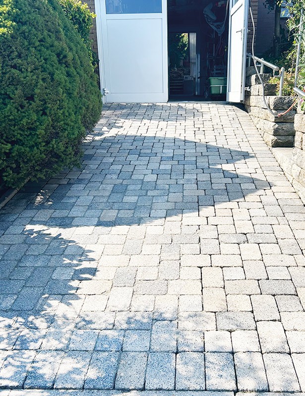 Gepflasterte Auffahrt mit offenen Türen im Hintergrund